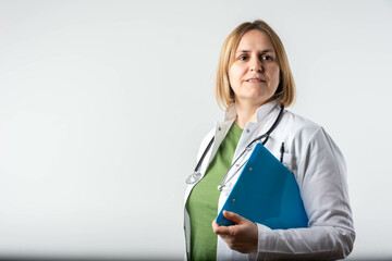 Happy smiling mature female doctor writing on clipboard, isolated on background. Medicine and health care concept. Smiling mature medical doctor woman with stethoscope.