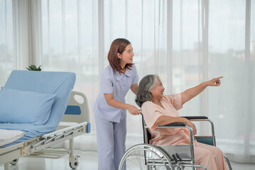 Asian nurse pushing senior female patient in a wheelchair at the hospital ward