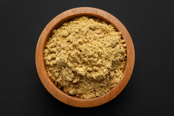 Dry ginger powder in bowl on dark table, top view