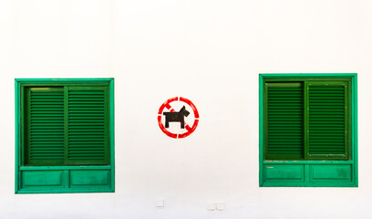 Znak zakazu wyprowadzania psów na tle białej ściany budynku w południowej Europie. © Majkol