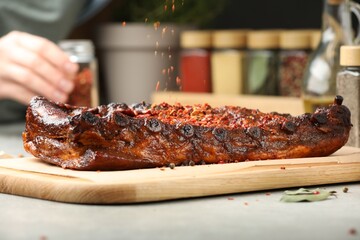 Woman adding spices to tasty dish at light table, selective focus