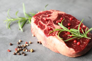 Piece of raw beef meat and spices on gray textured table, closeup