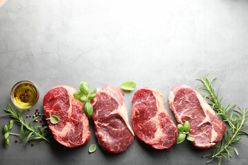 Pieces of raw beef meat and spices on grey table, flat lay. Space for text