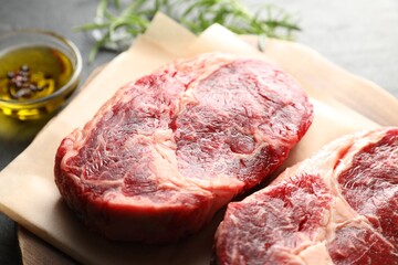 Pieces of raw beef meat and spices on table, closeup