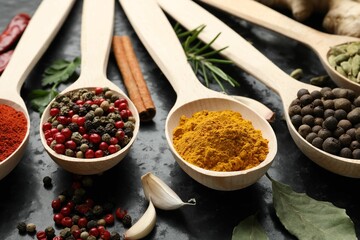 Many different spices in spoons on black table, closeup