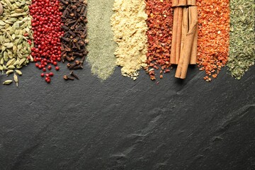 Many different spices on black table, flat lay. Space for text