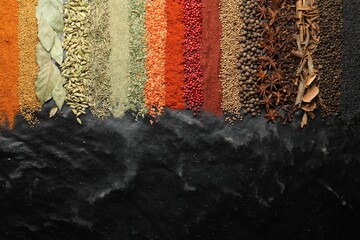 Many different spices on black table, flat lay. Space for text