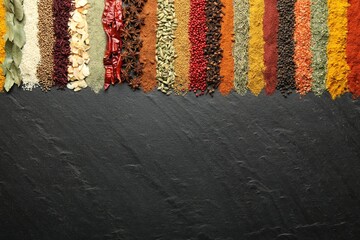 Many different spices on black table, flat lay. Space for text