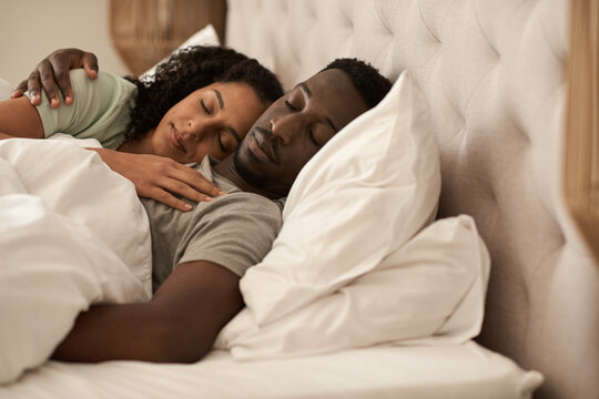 Young multiracial couple asleep in bed in the morning