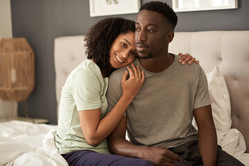 Affectionate young multiracial couple sitting in their bedroom in the morning