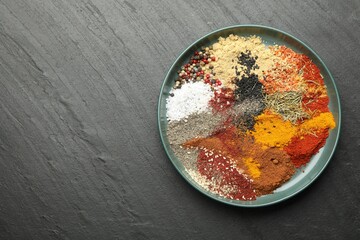 Different aromatic spices on dark textured table, top view. Space for text