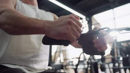 Gymnast seated on bench pulling cable roller with controlled motion and focused strength in gym with background people working out to capture dynamic training atmosphere and repetitive rowing action