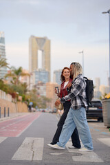 Fototapeta premium Young adults enjoy a casual stroll across the street in a vibrant city