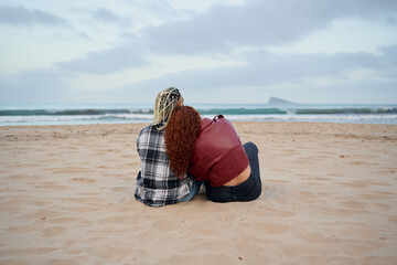 Two friends relax on the beach while enjoying a peaceful sunset view