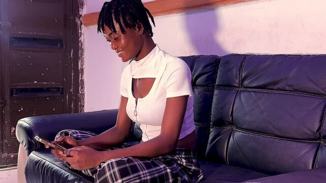 young black woman sitting leg crossed shopping online using phone and debit card