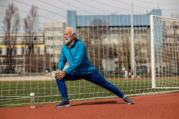 Obraz premium A senior sportsman is stretching his legs on stadium.