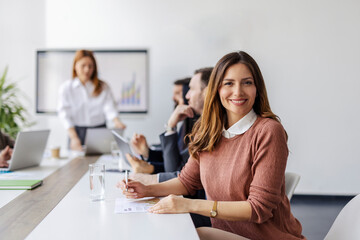 Portrait of female expert on presentation at boardroom smiling at camera.
