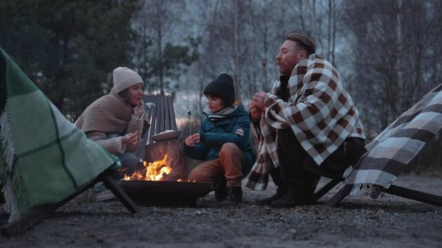 A family eats marshmallows that were roasted on the fire
