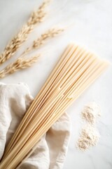 Bundle of raw spaghetti with flour and wheat stalks, top view