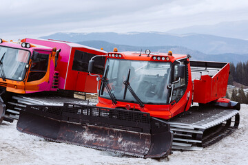 Machine for skiing slope preparations at background of mountains.