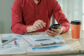 A focused businessperson works on summarizing annual performance results while multitasking by...