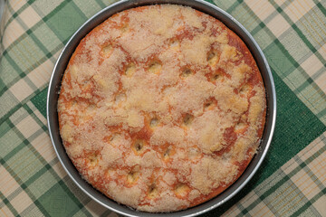 dolce di forma rotonda, fatto in casa con pane zuccherato, su una superficie di stoffa, dalle sfumature di colore verde, a quadri