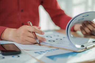 A focused businessperson works on summarizing annual performance results while multitasking by...