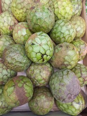Obraz premium Fresh cherimoya annona cherimola fruit display in market for culinary use. Green fruit background