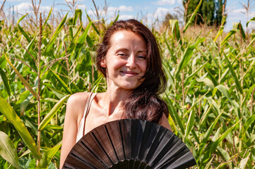 Happy girl with smiling face portrait hold black flamenco summer fan in hot cornfield, geisha...