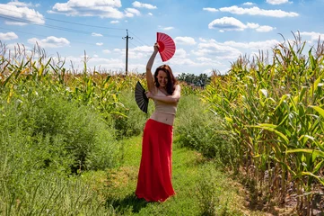 Global tourism. Feminine freedom. Folkloric girl travel. Flamenco dancer. Beautiful woman in red skirt with fans dance in field. Folk culture. Traditional dance flamenco. Artistic lifestyle