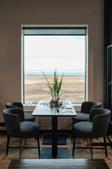 Scenic dining table with minimalist setup and large window with desert field view