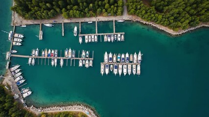 Tranquil Marina Vista: An aerial shot offers a serene panorama of a marina filled with docked boats, embraced by the calming turquoise waters. Capturing the allure of the open sea.
