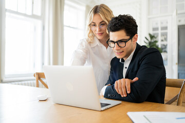 Obraz premium Bright workspace collaboration between two professionals with engaging expressions and a laptop