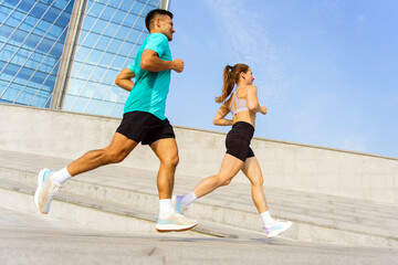 Couples jog together in the city under a clear blue sky during early morning hours
