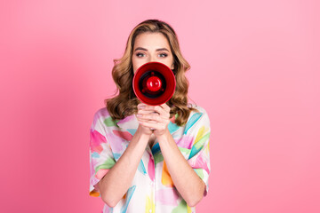 Young woman with stylish printed shirt holding a red megaphone against a pink background promoting...