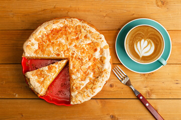 Homemade pie decorated with meringue and a cup of coffee cappuccino on a wooden table. Top view.
