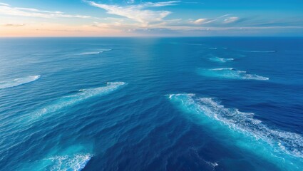 A broad view of an endless horizon where the azure ocean meets the sky, accompanied by white-capped waves in the distance, stirring feelings of immensity and fascination.