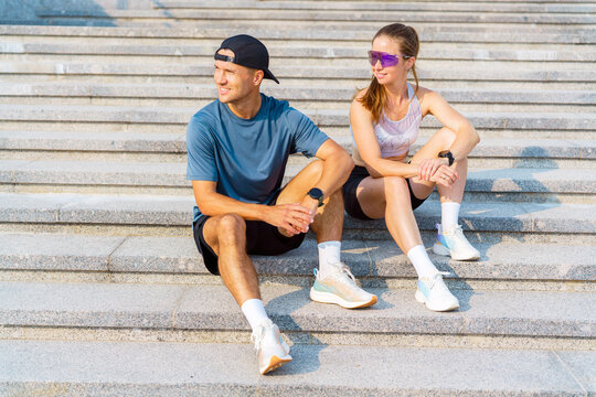 Couple takes a break on outdoor stairs after a refreshing morning run in the warm sunshine