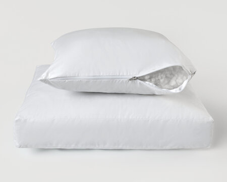 White pillow with open zipper revealing filling material resting on another pillow