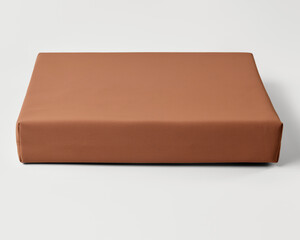 Modern light brown yoga bolster resting on white surface