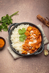 Aromatic Indian chicken tikka masala served with rice and coriander, turmeric, garlic, cinnamon sticks, traditional dish of India top view