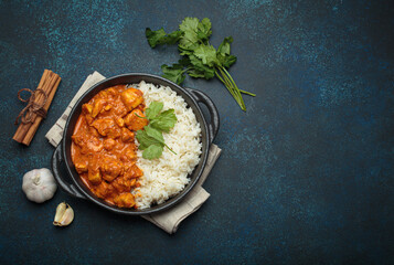 Indian chicken tikka masala in a creamy tomato sauce, served with basmati rice, fresh coriander and spices, traditional dish of India top view, copy space