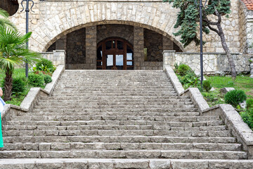 A wide monumental staircase made of stone blocks leads from the embankment to the historic building. The absence of a fence gives it a strict and majestic appearance.