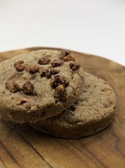 Chocolate chip cookies on a wooden board with a white background