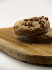 Chocolate chip cookies on a wooden board with a white background