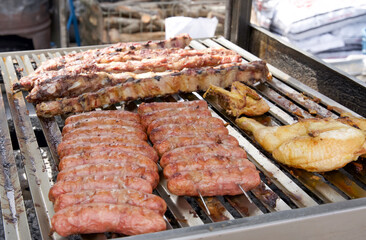 Grilled meats including sausages, ribs, and chicken on a barbecue grill, showcasing delicious food preparation and outdoor cooking experience