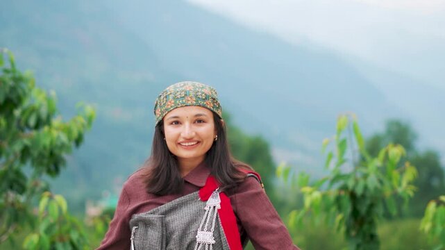 Portrait of beautiful Himachali woman wearing traditional Kulluvi dress Pattu and scarf known as Dhatu. Tribal female standing in Himalaya mountains in Manali, Himachal Pradesh, India. 