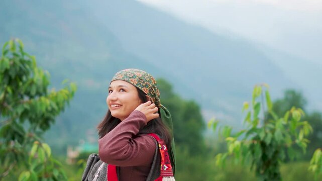Portrait of Indian tribal woman standing in mountains. Himachali woman wearing traditional headscarf known as Dhatu and dress Pattu. Female wearing traditional attire of Shimla, Manali.