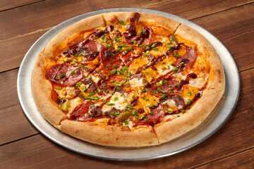 Delicious pizza with salami, beef, cheddar, and chives resting on wooden table