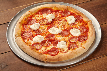 Delicious pepperoni pizza with creamy ricotta and grated parmesan cheese on wooden table